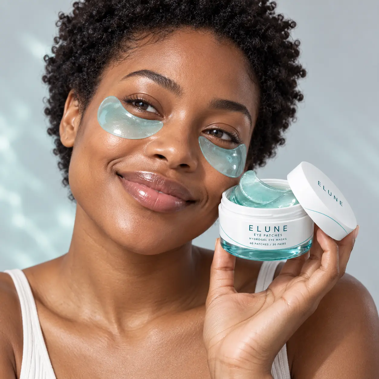 Woman smiling while wearing ELUNE aqua eye patches