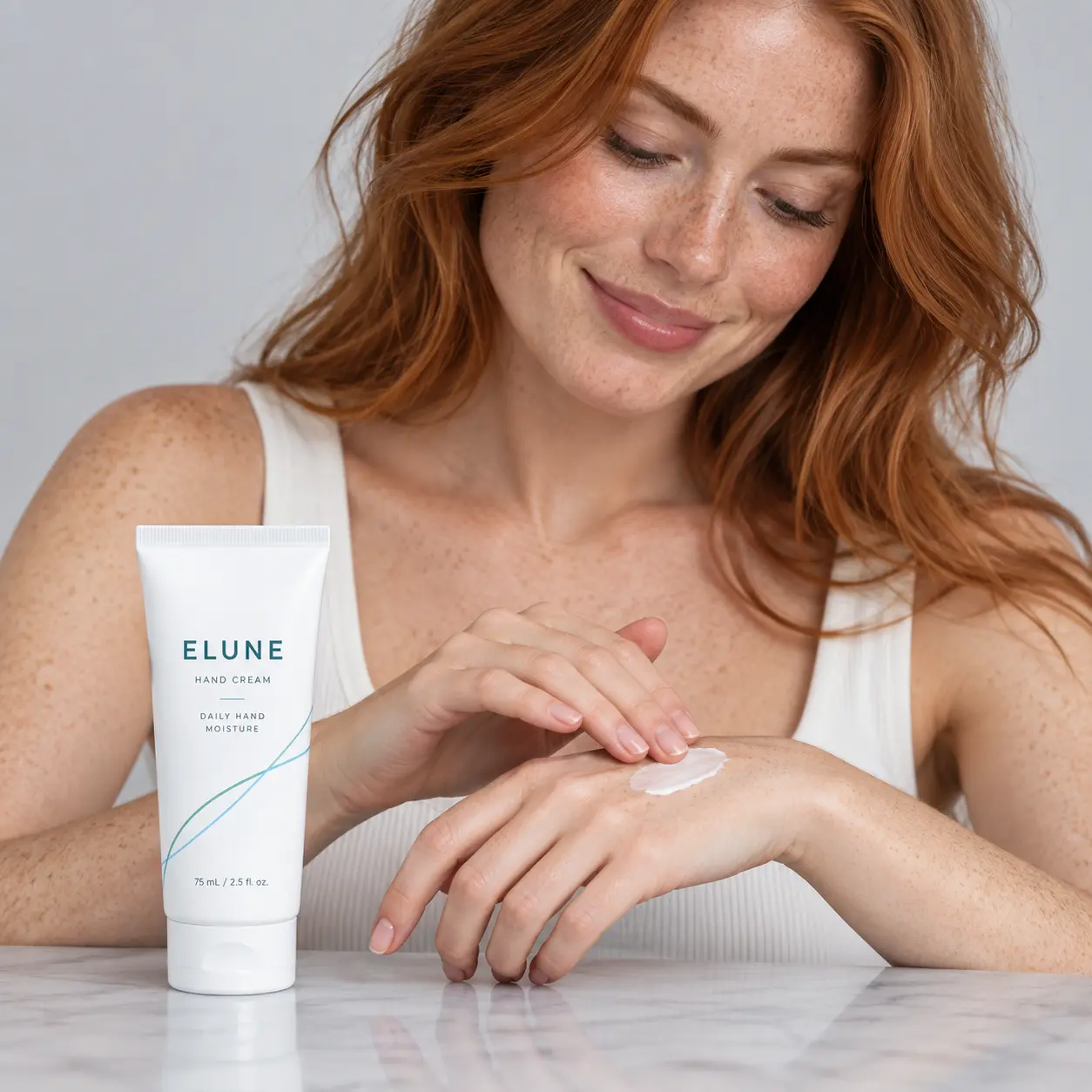 Freckled woman massaging ELUNE Hand Cream into her hands