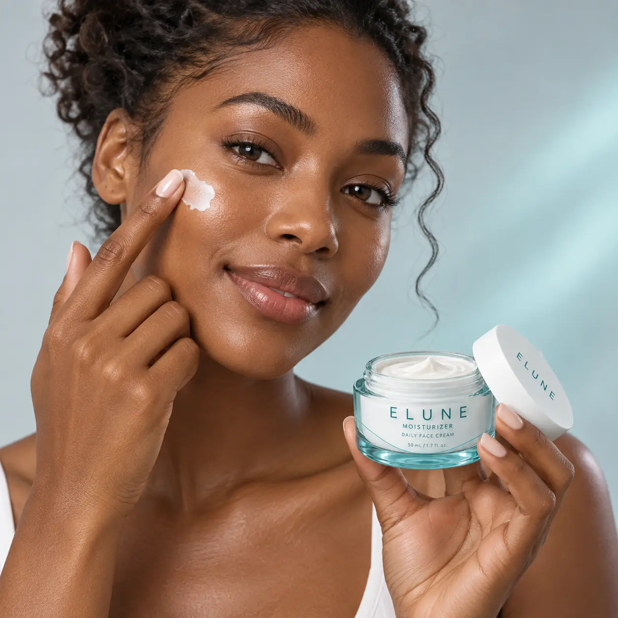 Woman applying ELUNE Moisturizer to her cheek